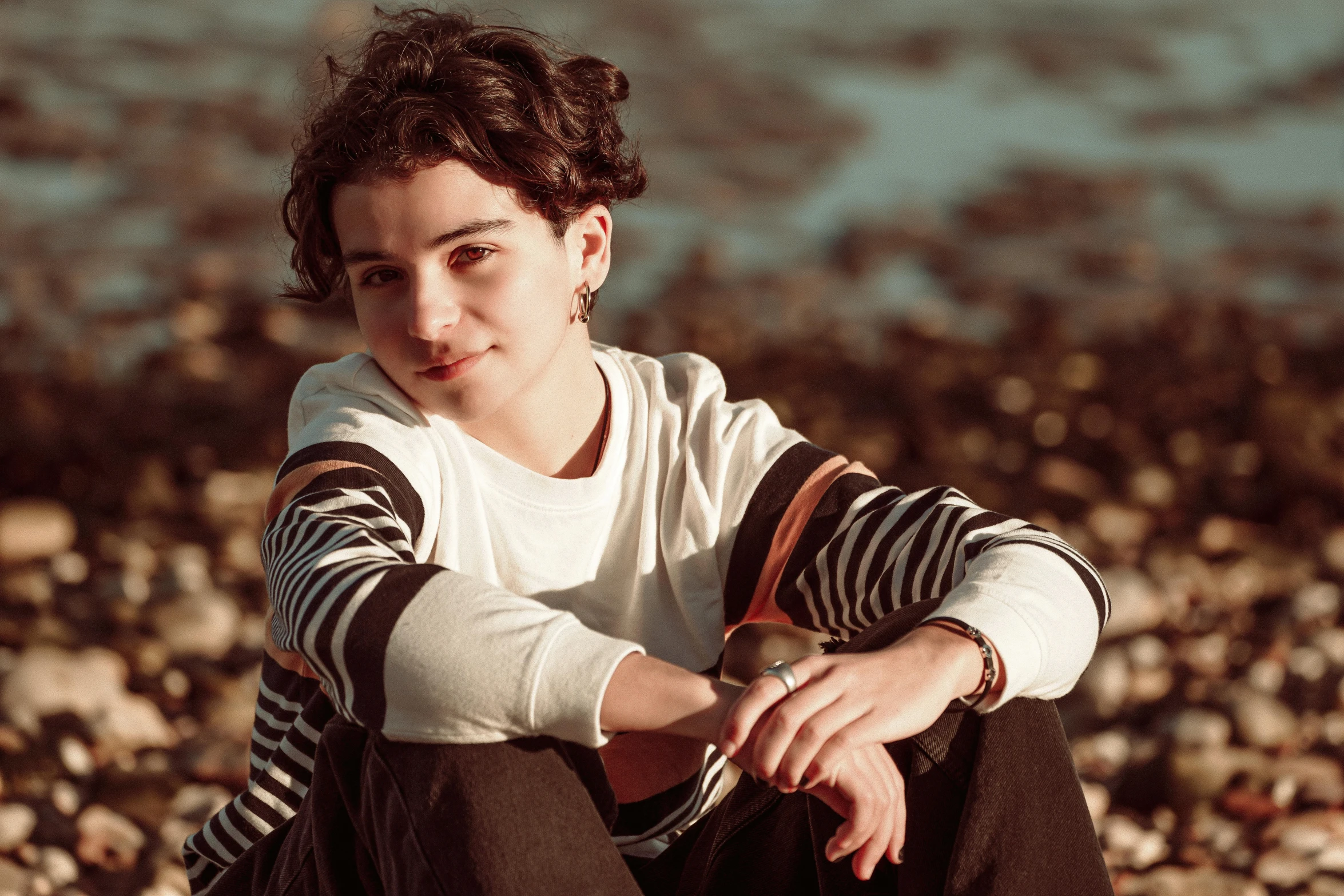 the boy sits on the beach in front of the rocks