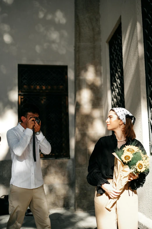 man and woman standing outside an old building and taking pictures