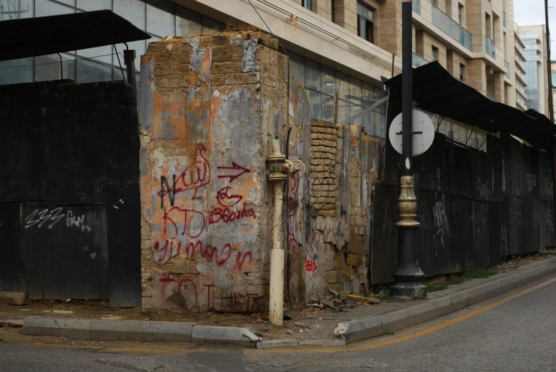 an empty street next to a wall covered in graffiti