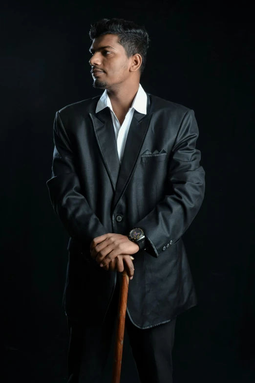 a man with a black jacket and white shirt in front of a black background