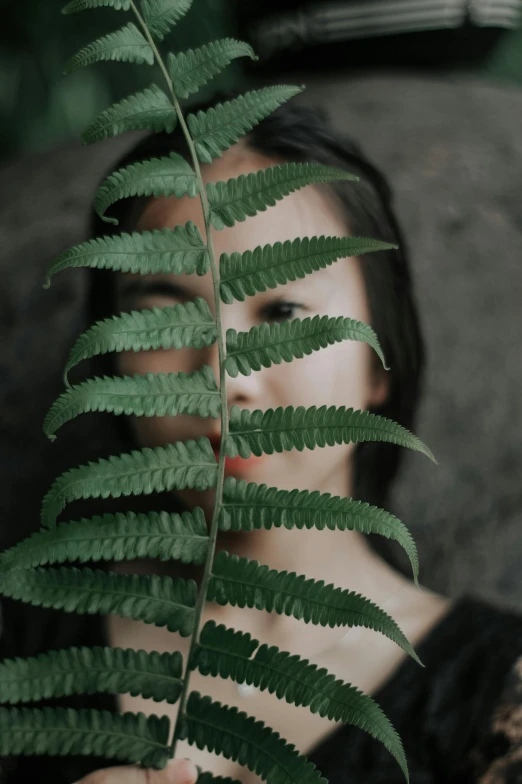 a girl is holding a large fern leaf