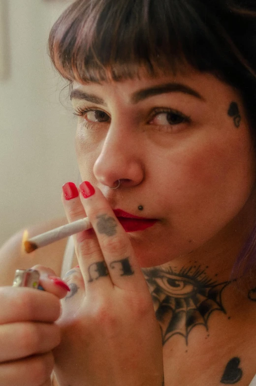 a woman holding a cigarette and looking at the camera