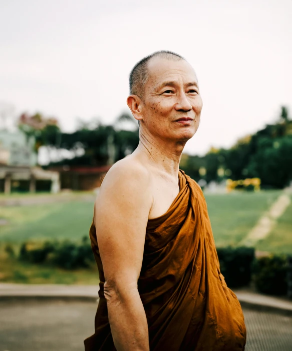 a man in a brown dress with a tree behind him