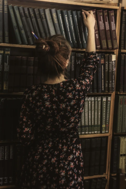 a woman writing on a book shelf in front of a bookcase