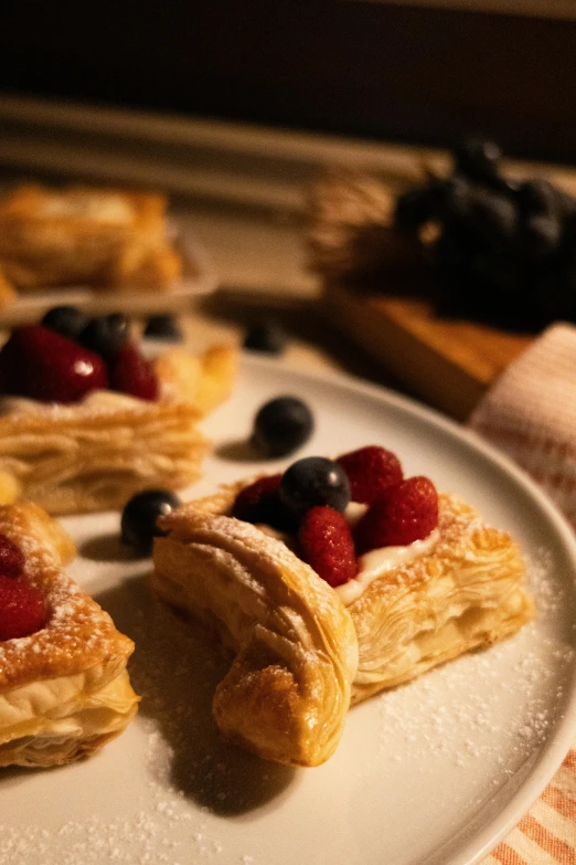several pastries on a plate with berries and blueberries