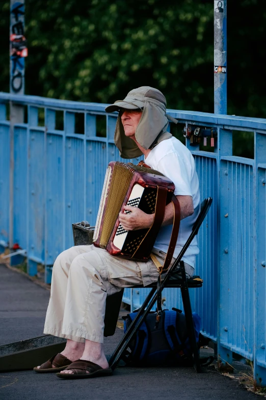 an old man sitting on a bench playing a bugle