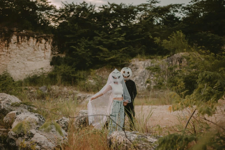 a newly married couple standing in the field by some trees