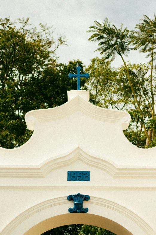 an archway has a cross and a blue sign on it