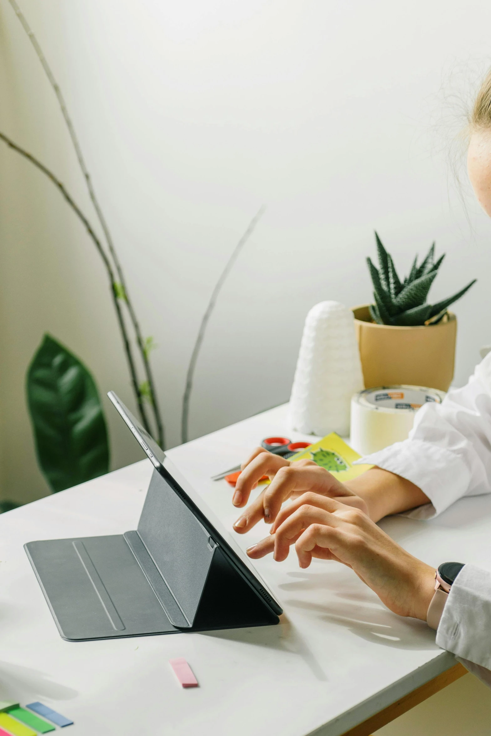 a little girl sits at a table while using a laptop