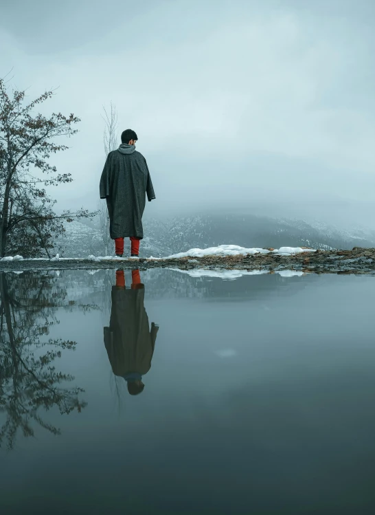 man looking at a lake in a jacket while standing on water