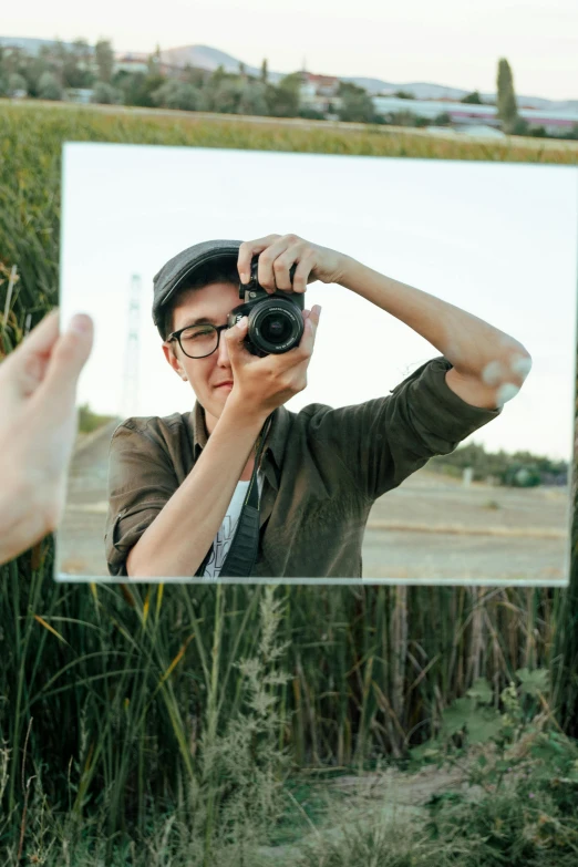 a person holding a camera in front of a mirror