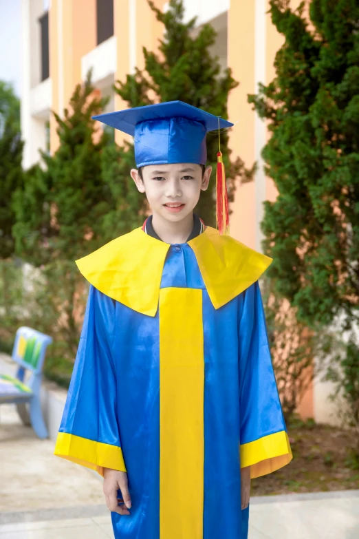 a boy wearing a blue and yellow graduation cap and gown