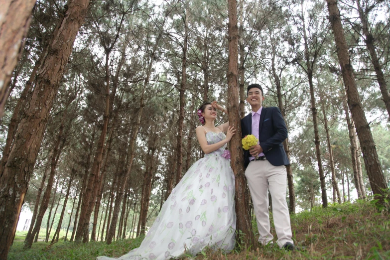 two people in wedding dresses stand in the forest