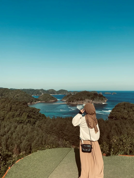 a person taking pictures of the water from top of a mountain