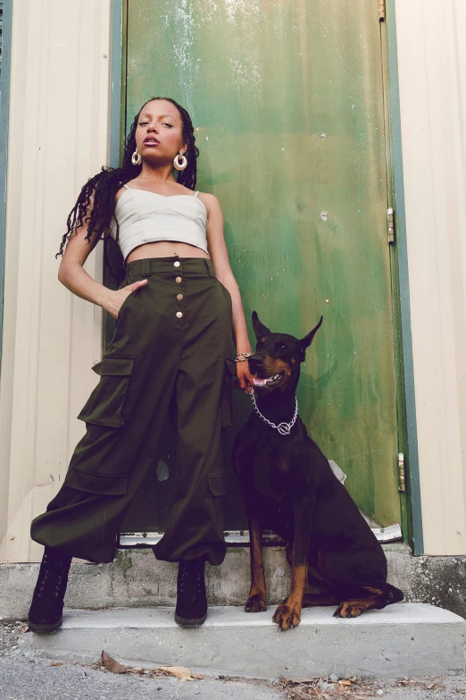 a woman standing next to a black dog in front of a door