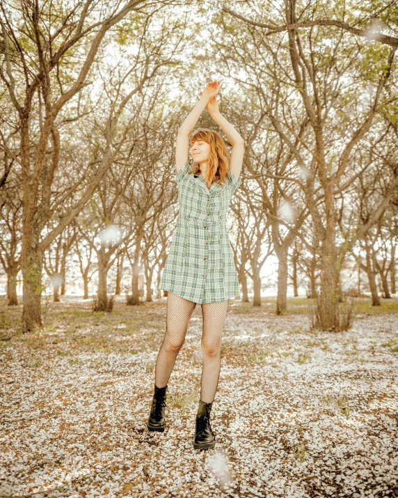 a woman wearing boots holds up her hands in a forest