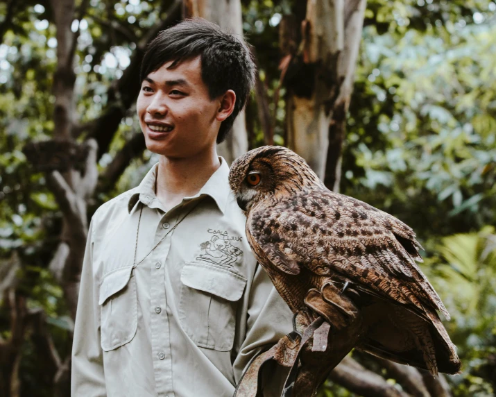 the man smiles as he holds an owl in his hand