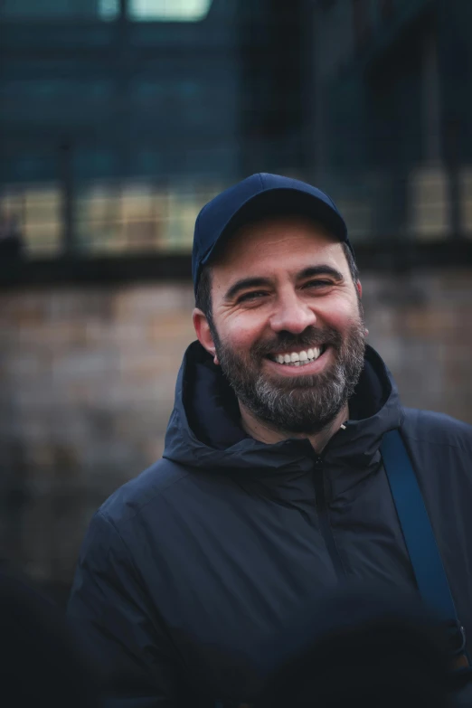 a man with a beard is smiling and wearing a jacket