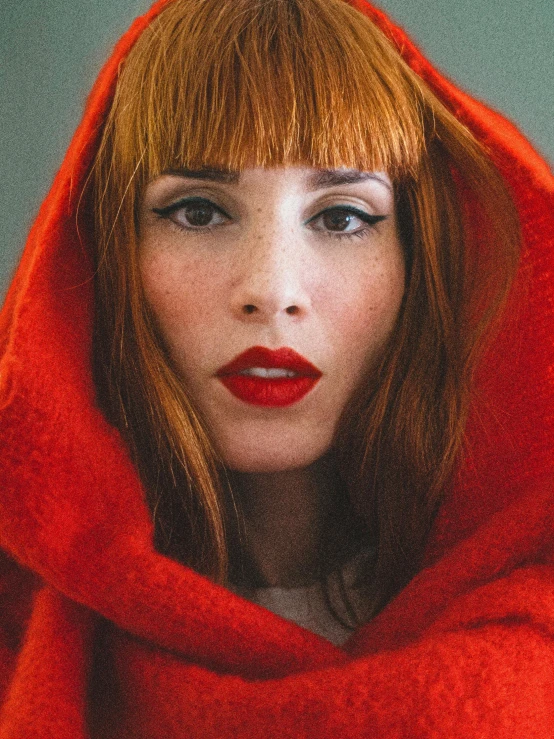 a woman with red lipstick and hood on