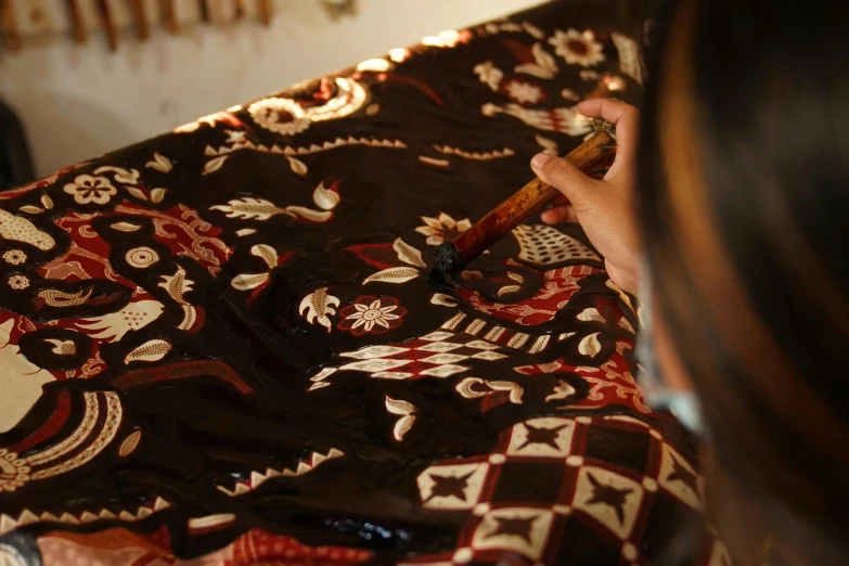 a person drawing designs on a cloth with a crayon pen