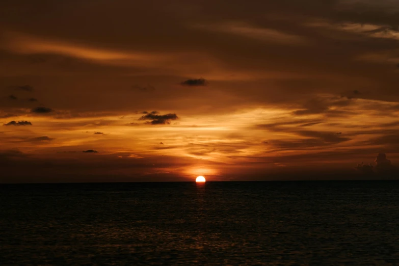 a boat in the ocean under a sunset