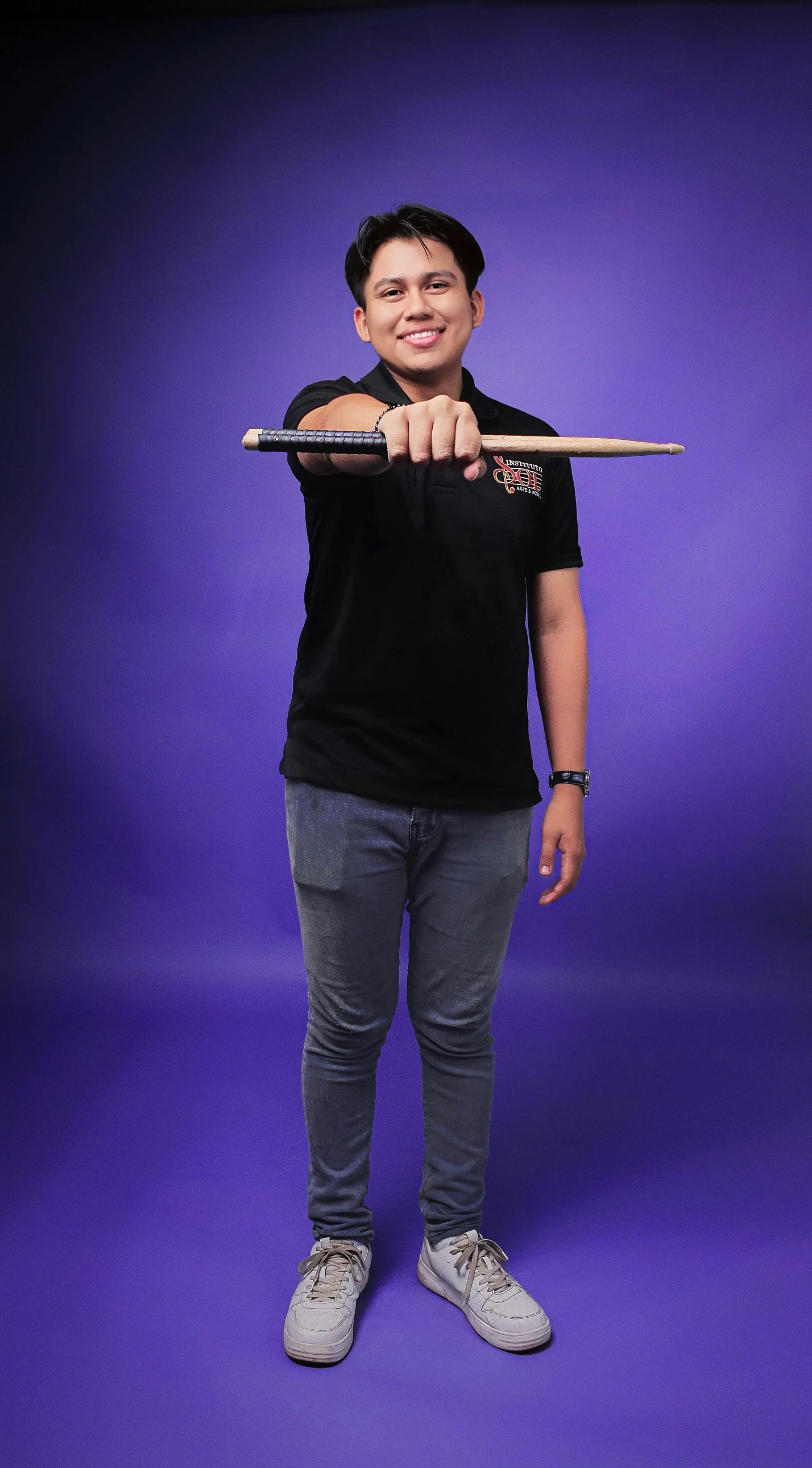 a smiling man holding a baseball bat with purple backdrop