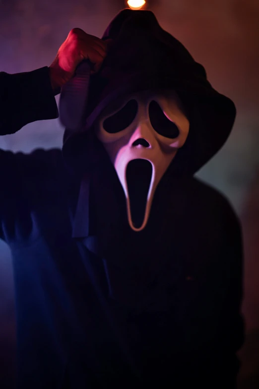 a person with a hood and mask on, putting his mouth wide open