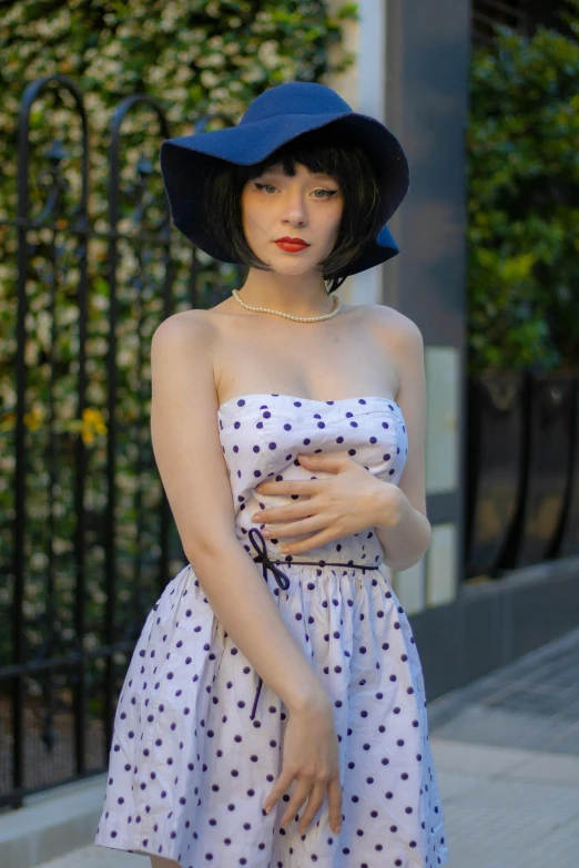 woman wearing a polka dotted dress and blue hat