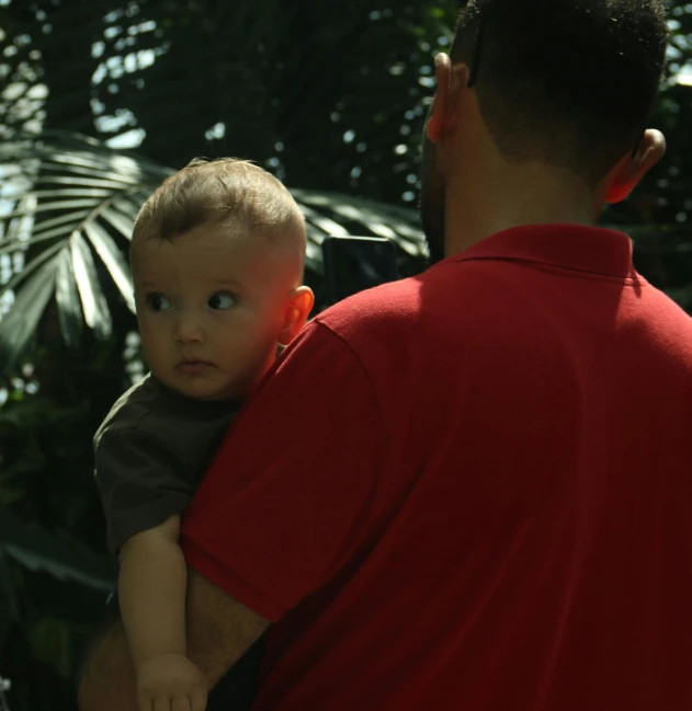 a man holds a baby and looks away from him