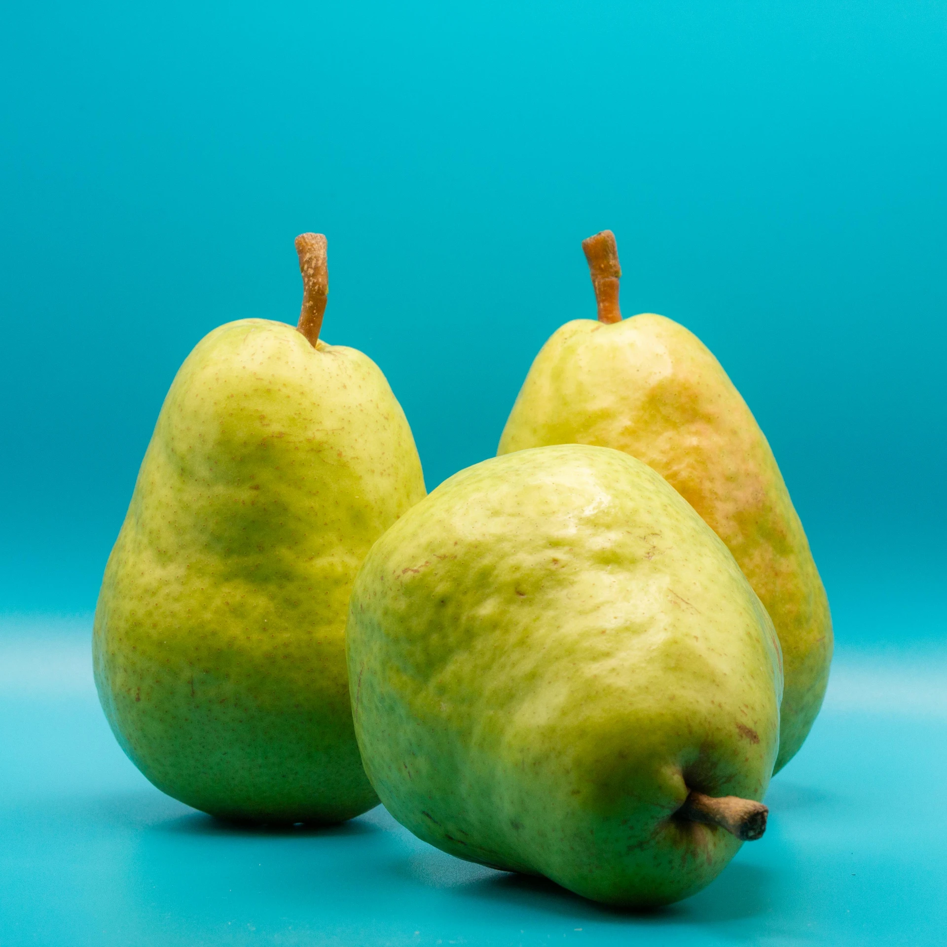 two pears and one apple are shown with a blue background