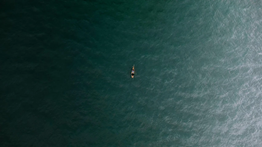 an aerial view of a person on a small boat in the middle of a body of water