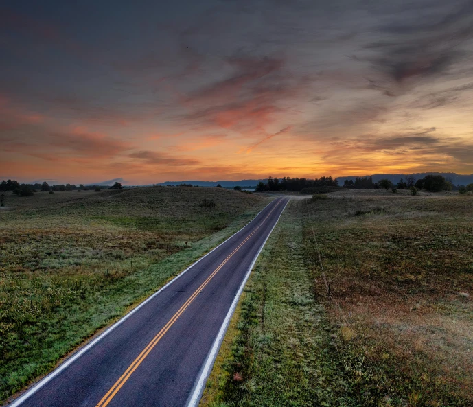 a rural road is passing under a cloudy sky