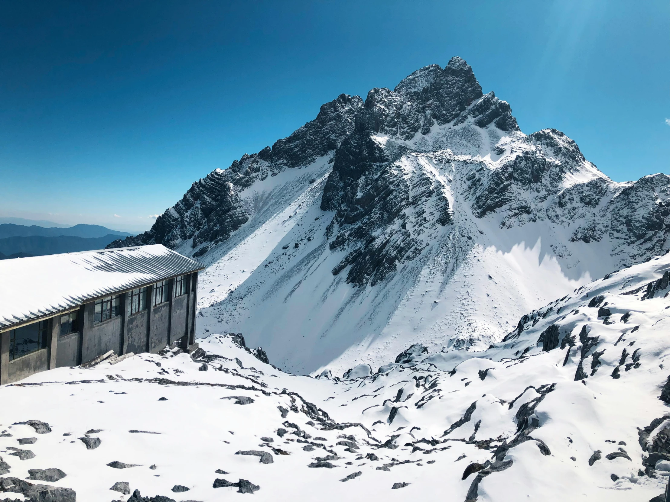 a snowy mountain covered in snow with a building