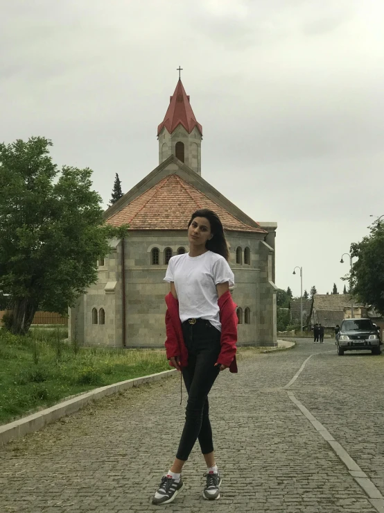 a woman standing on the street in front of a church