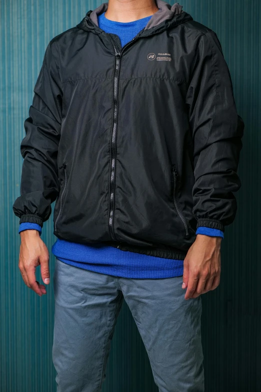 a young man in a jacket standing against a blue background