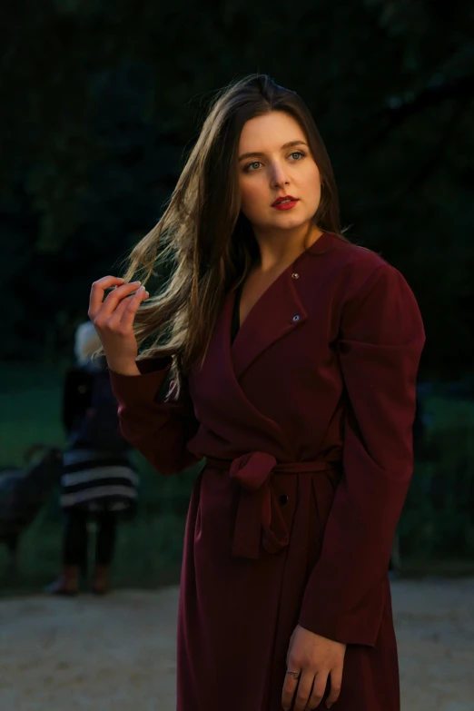 a woman in a long maroon coat standing next to other women