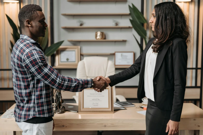 there are two people shaking hands together at a desk