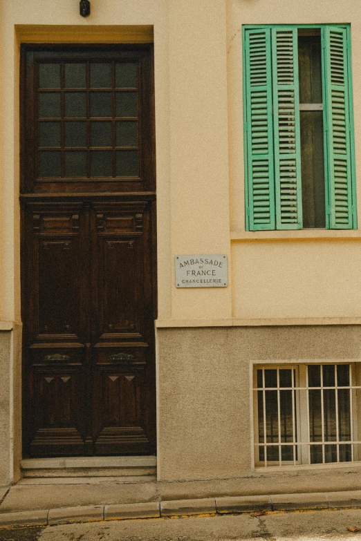 a wooden door with green shutters is next to a window