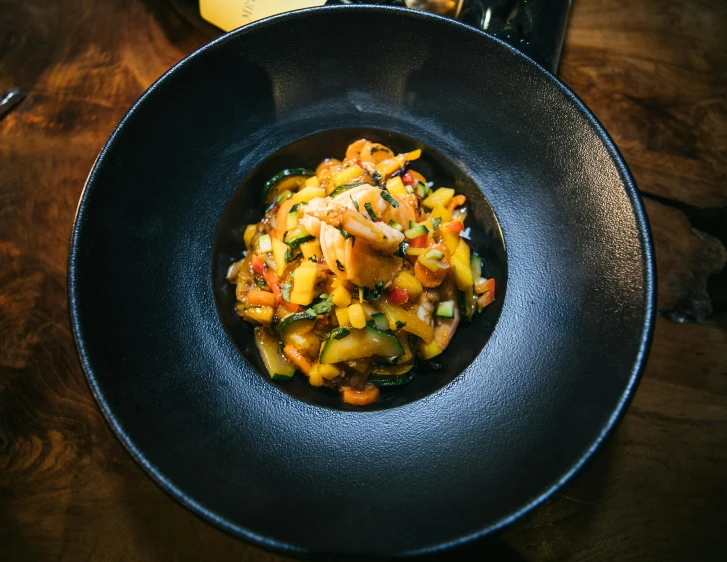 some food in a black bowl sitting on a table