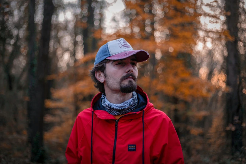 man standing in the woods with trees turning orange