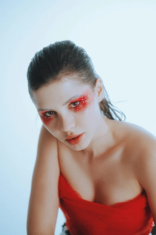 a beautiful woman wearing makeup and dress sitting down