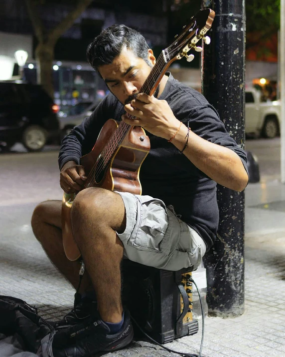 a man is sitting on the street playing an instrument