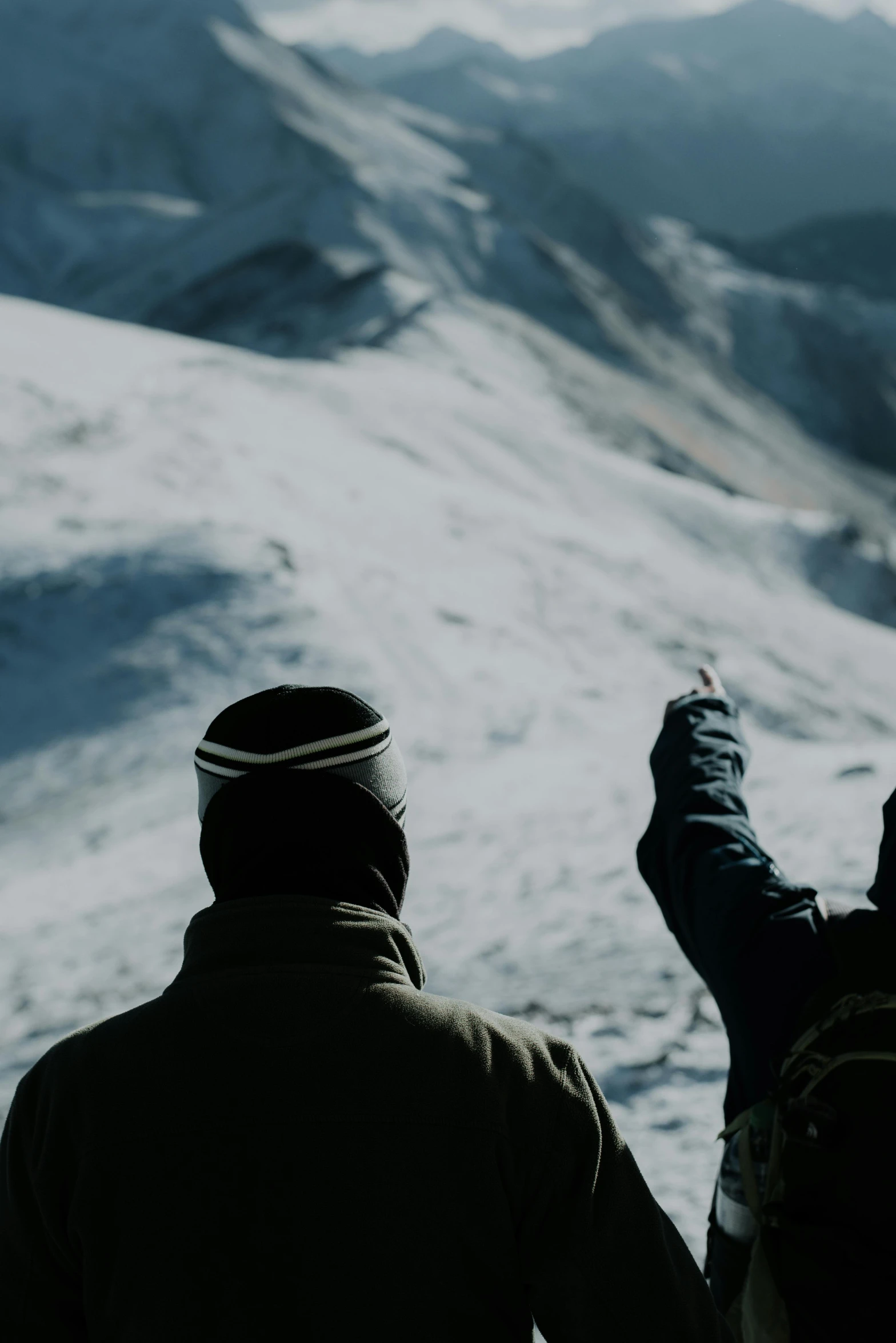 two people standing on a hill pointing at the sky