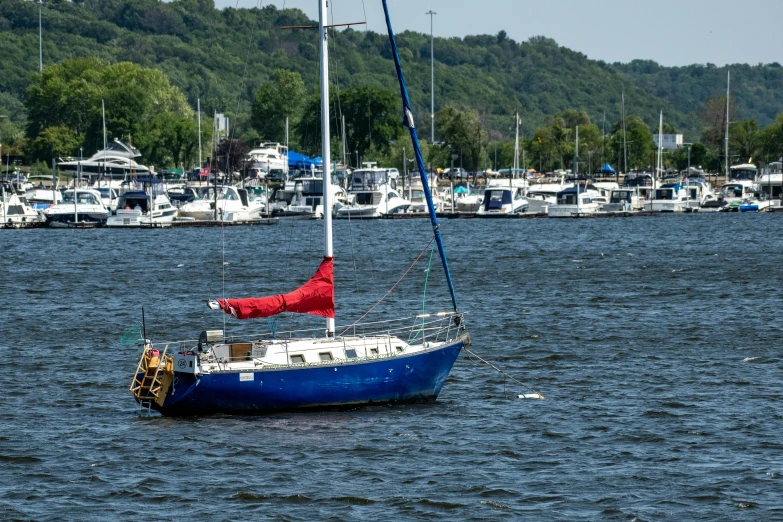 a blue sailboat with a red sail is in a harbor