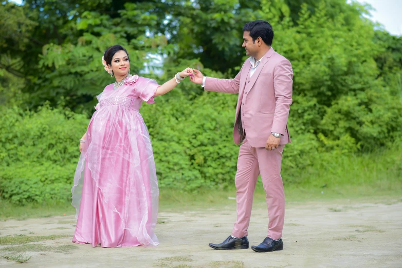 a man and woman dressed in pink are holding hands