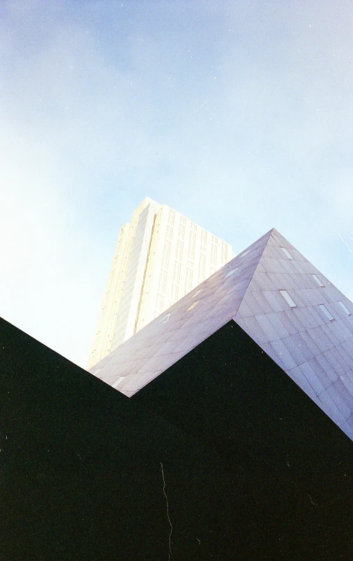 a black triangular and concrete building with a white sky behind