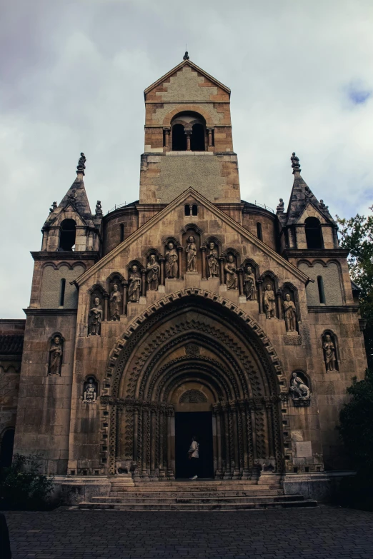 a church building with stone and arches under a cloudy blue sky