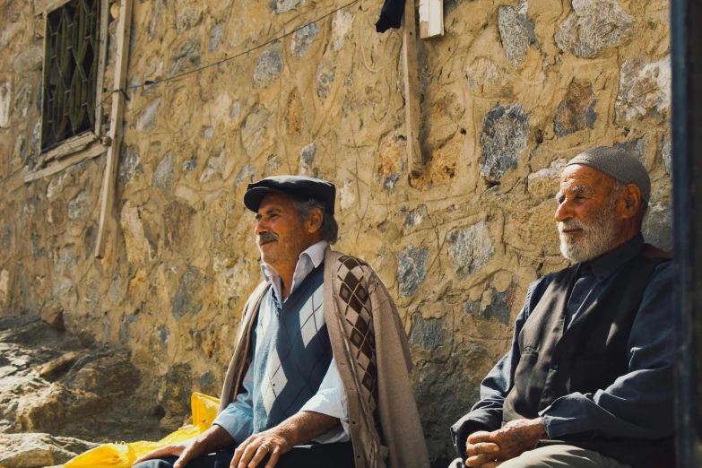 two old men sitting down together on the street