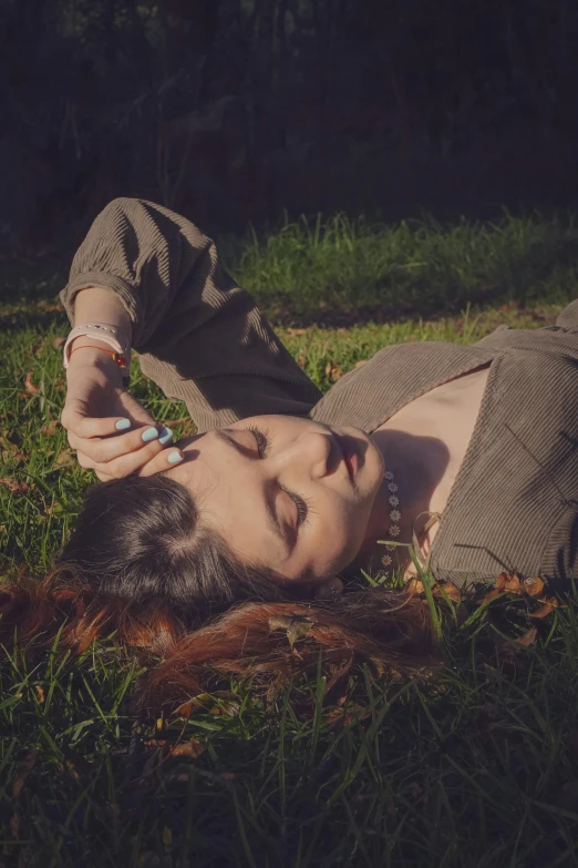 the young woman lays in the grass with a cigarette