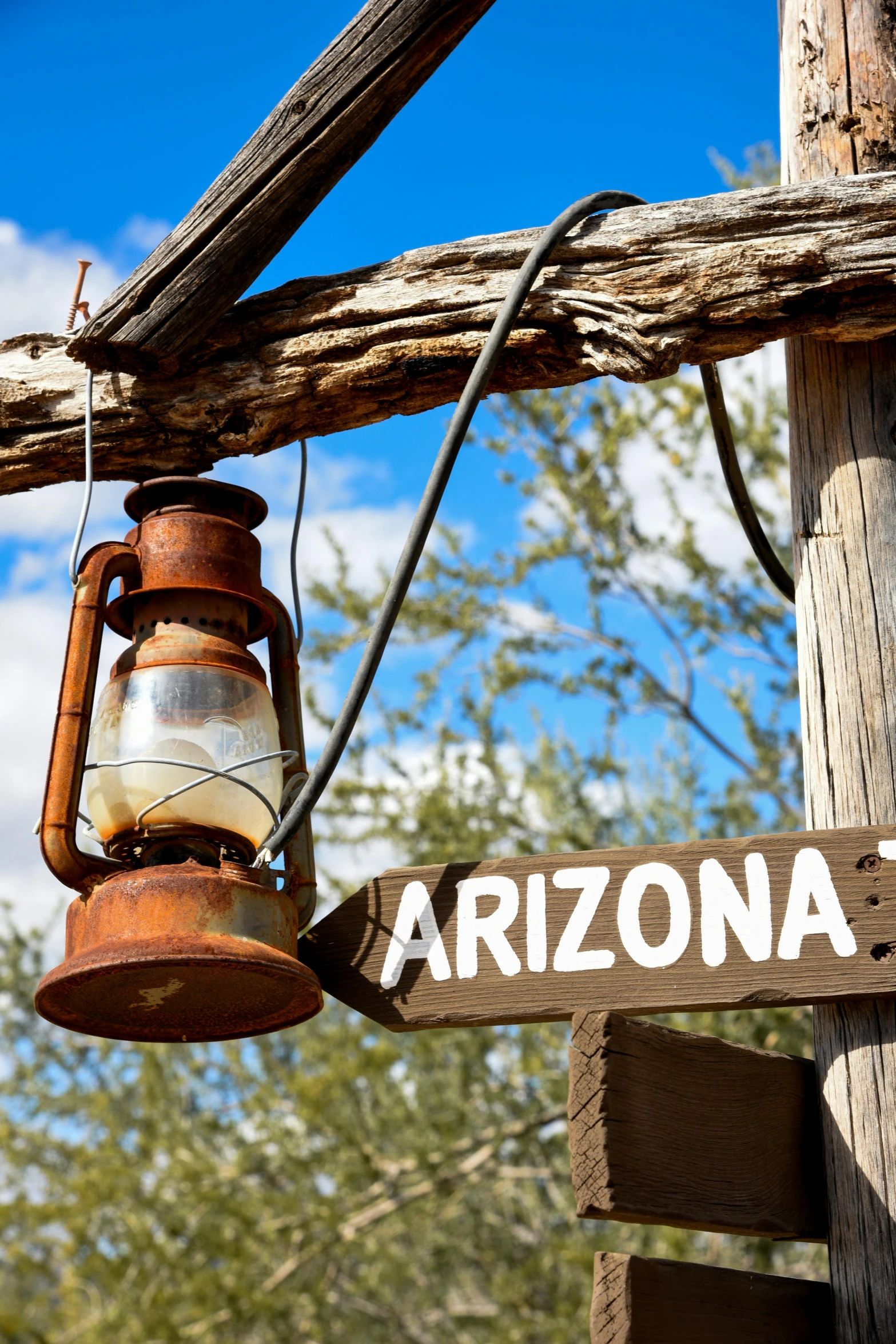 a wooden sign pointing to arizona with a lantern